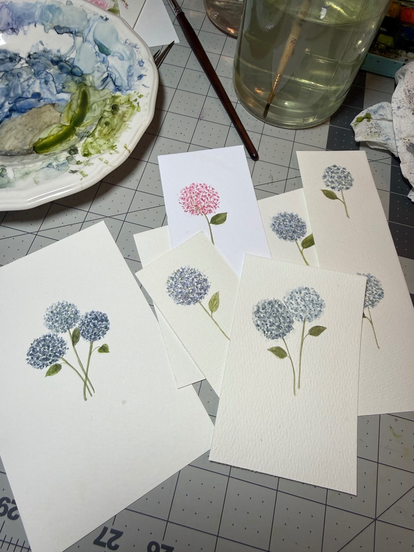 Pink and blue hydrangea studies beside a watercolor palette