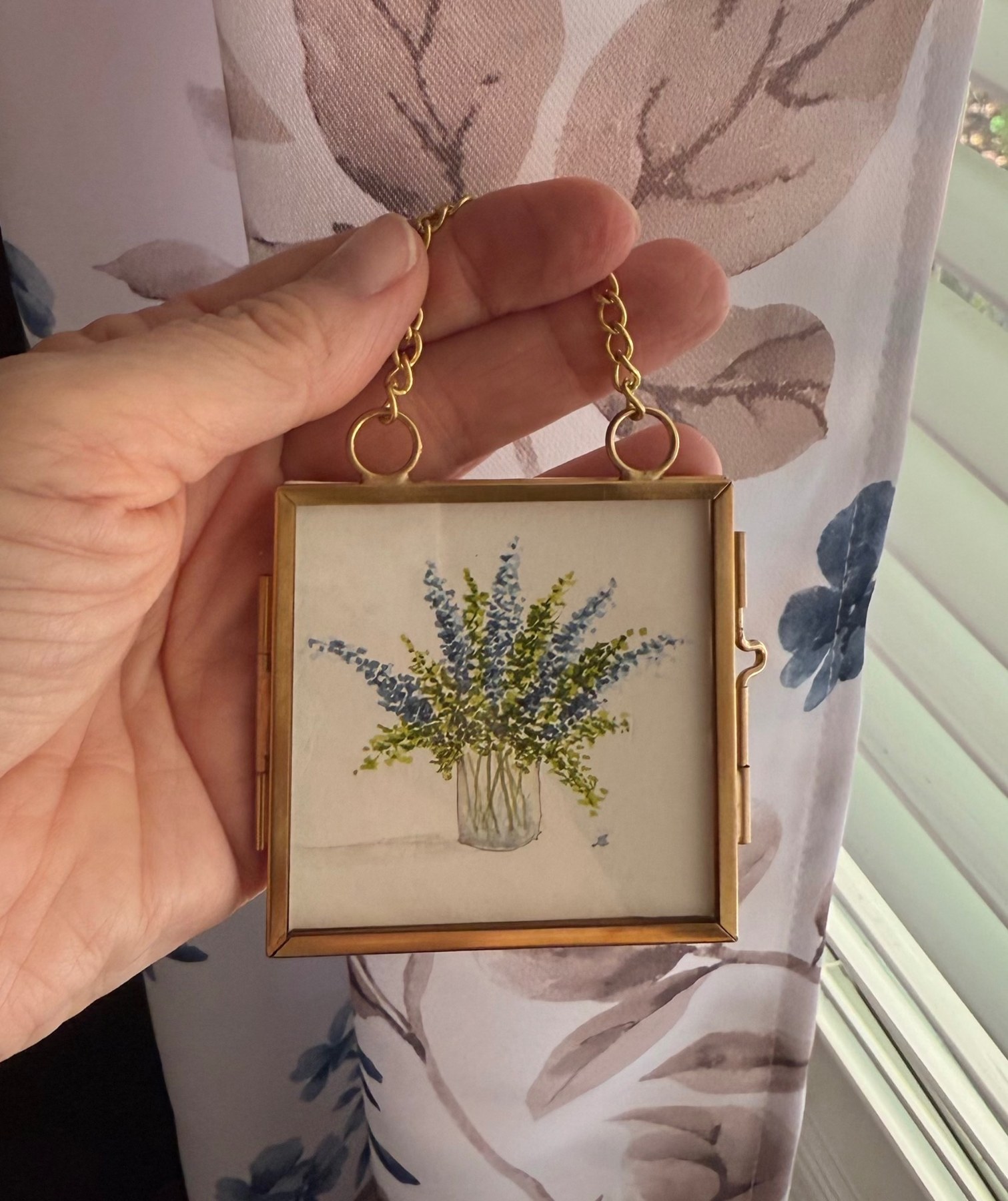 A miniature gold frame containing a lavender bouquet