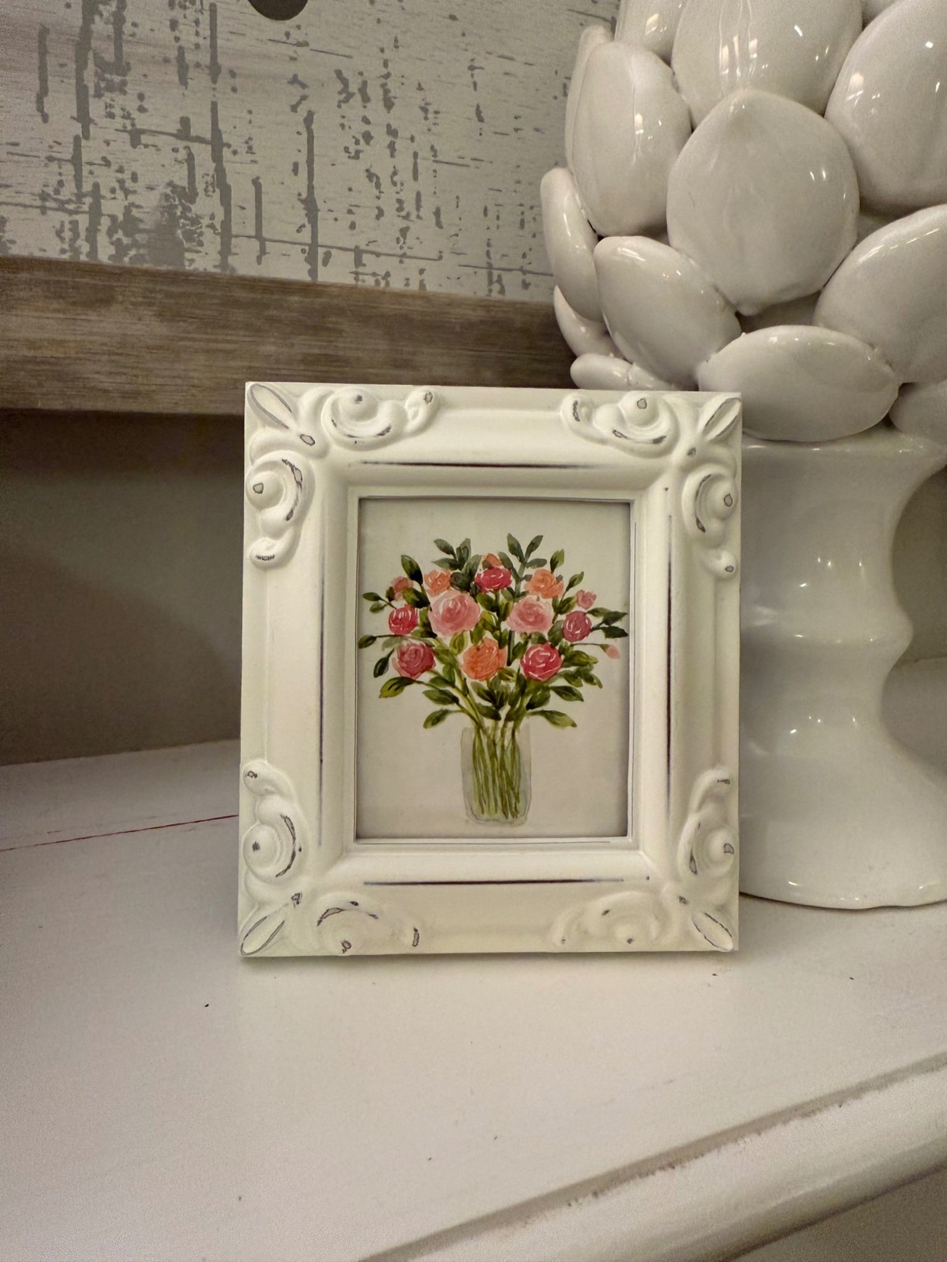 Framed pink and red bouquet displayed on a shelf