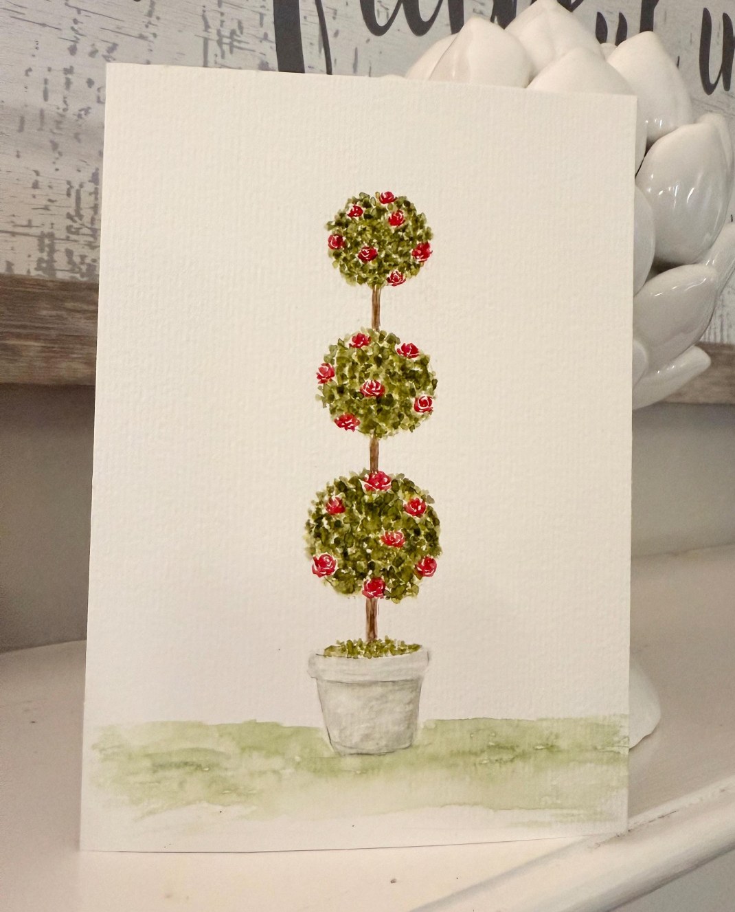 Three flowering topiary spheres in a gray pot