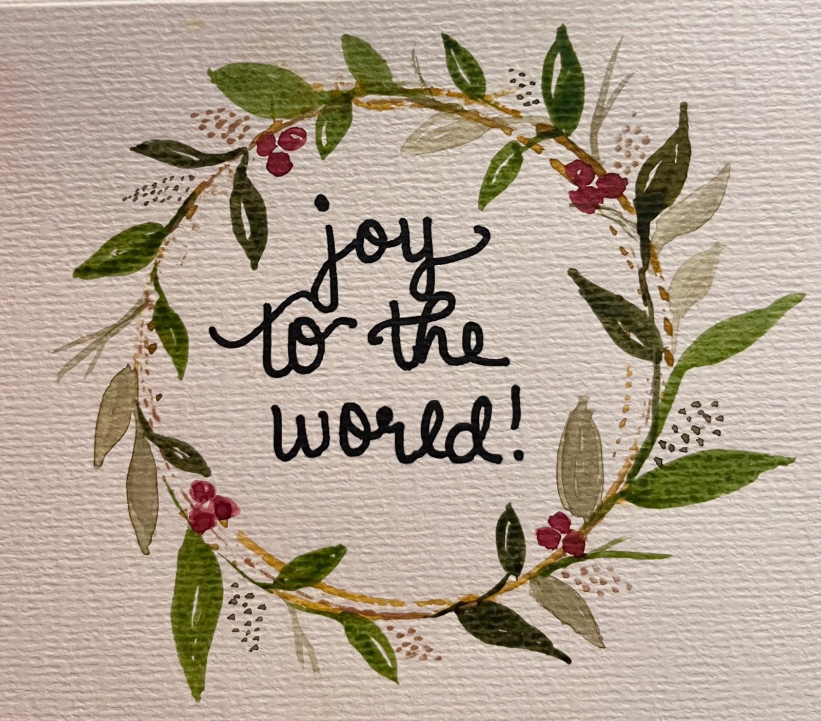 Hand-lettered Joy to the world inside a botanical wreath