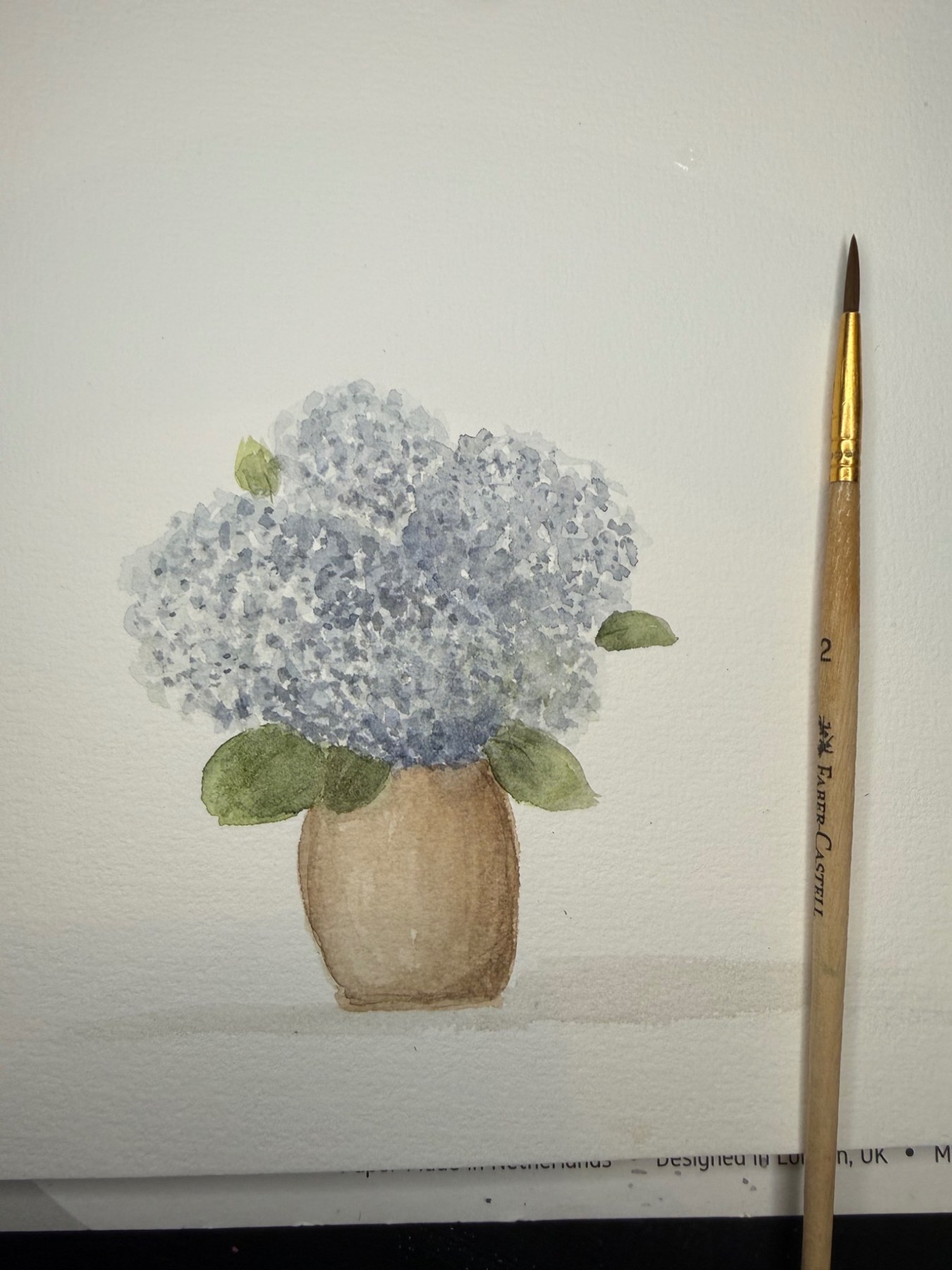 Blue hydrangea bouquet beside a paintbrush