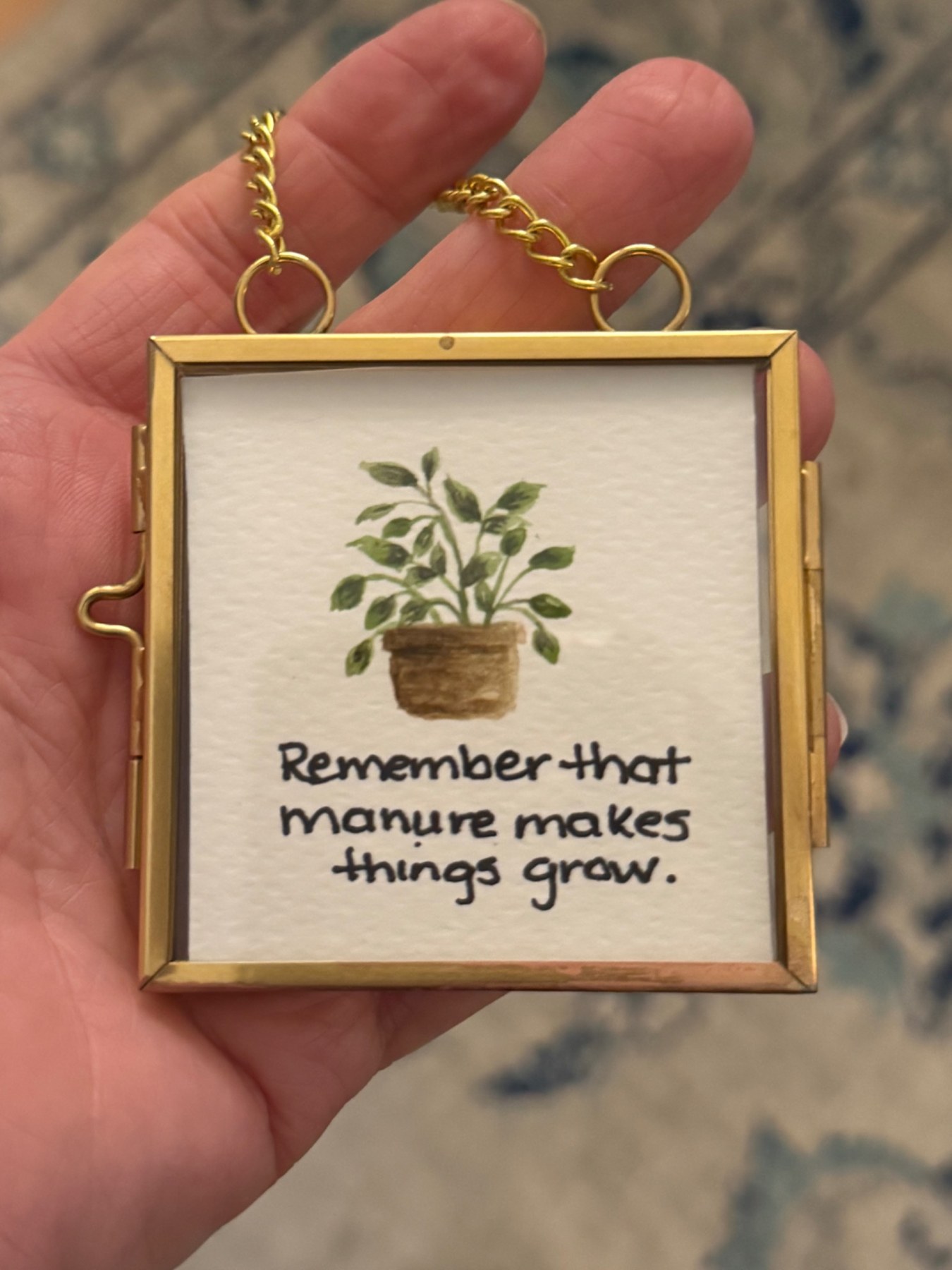 Miniature gold frame with a painted plant and playful lettering